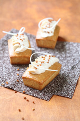 Rectangular Cakes with White Chocolate Cream Cheese Frosting decorated with caramelized walnuts, on a wooden table.