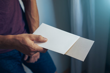 young man holding a white & brown blank envelopes