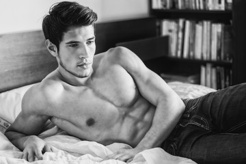 Shirtless sexy male model lying alone on his bed