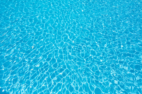 Water surface in swimming pool with sun reflection