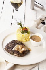 beef steak with a sauce and mash potato on a white background