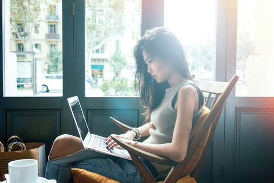 Beautiful young Asian girl working at a coffee shop with a laptop.female freelancer connecting to internet via computer