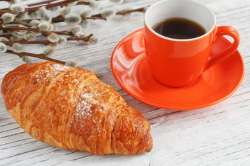 Cup of coffee and croissant with pussy willow