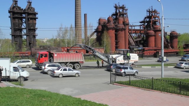Cold planer remove worn asphalt into dump truck during repairing road works. Removing the old asphalt occurs while driving 