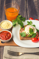Breakfast toast with poached egg, tomato sauce, basil and parmes