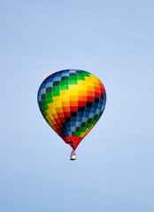 Colorful hot air balloon moving up in blue sky.