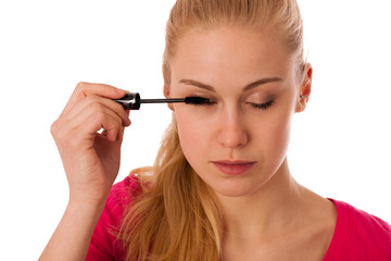 Woman applying black mascara on eyelashes, doing makeup.