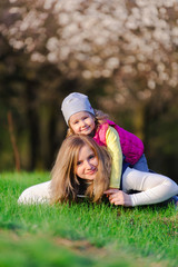 Little girl and her mother hugging outdoors on spring meadow