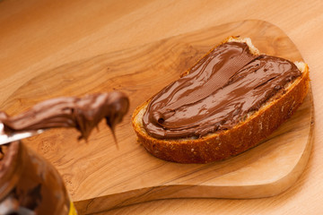 Slice of bread with sweet chocolate nougat spread on wooden back