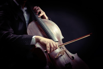 Man playing on cello on dark background