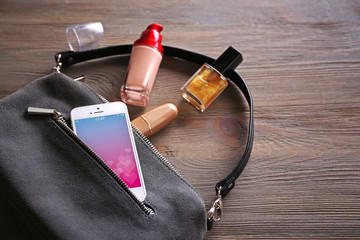 Ladies handbag and smartphone with romantic screensaver on gray background