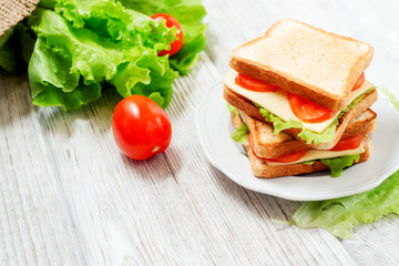 
breakfast or lunch , sandwiches with cheese , sausage , tomato, lettuce and mayonnaise on a wooden background