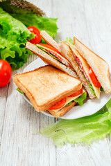 
breakfast or lunch , sandwiches with cheese , sausage , tomato, lettuce and mayonnaise on a wooden background
