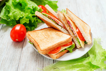 
breakfast or lunch , sandwiches with cheese , sausage , tomato, lettuce and mayonnaise on a wooden background