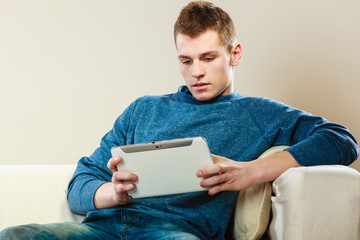 Young man with tablet sitting on couch at home