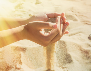 Sand pours through the fingers of a young girl