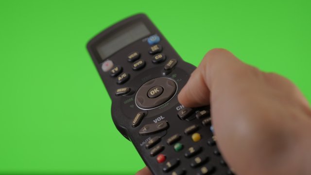 Remote control changing channels in front of green screen background 4K 3840X2160 UltraHD video - Remote control in male hand channel change chroma green screen 4K 2160p UHD footage