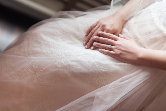 Bride hands on wedding gown