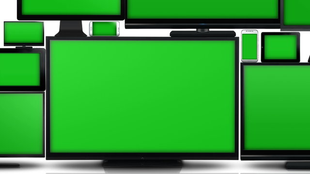 Many different types of screens. TVs, computer monitors, smartphones and tablets. They laid on each other in a pile isolated on a white background. They are all with a green screen. Zoom in..