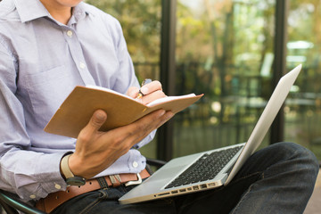 Handsome man working with smartphone, laptop and documents at ou