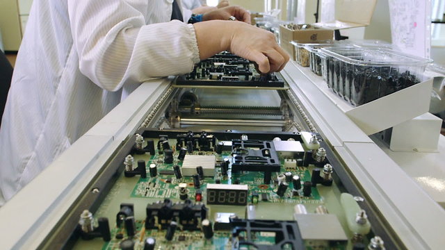 Workers are manufacturing Circuit Boards in Electronics Factory - Assembly line of LEDs, Transistors and other Electronic components being installed