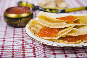 Pancakes with red caviar on a table.