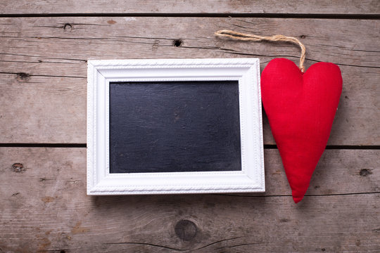 Red decorative  heart and empty blackboard on aged wooden backgr
