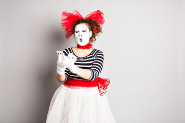 The young girl actress is holding a cell phone and looking at the screen with a surprised expression