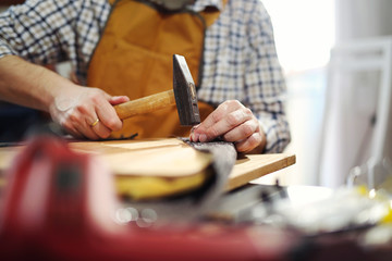 Carpenter working with hammer in his workshop, close up
