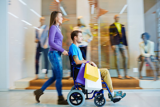 Pretty girl shopping with her disable boyfriend in wheelchair