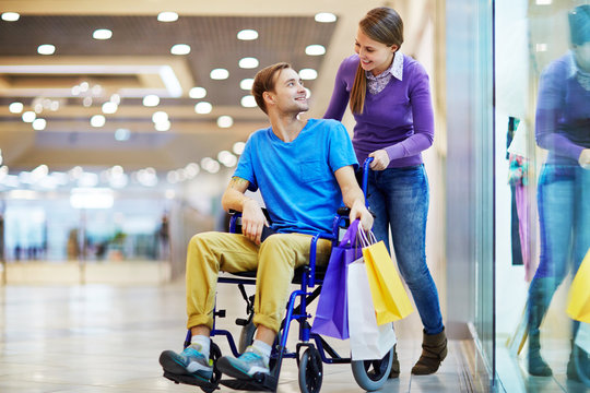 Caring girl talking to her boyfriend in wheelchair during sale