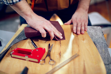 Carpenter sanding plank in his workshop