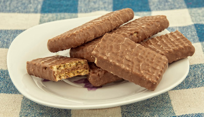 Plate with chocolate wafers on table.
