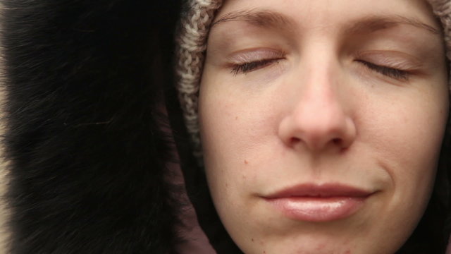 young girl in winter clothes chews the cud, outdoors
