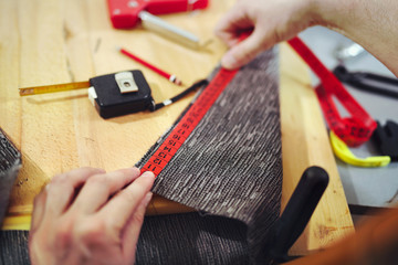 Man upholstering chair in his workshop, measure