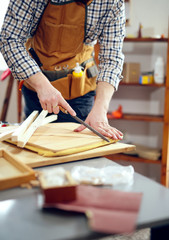 Man upholstering chair in his workshop. Carpenter using rasp in the carpentry
