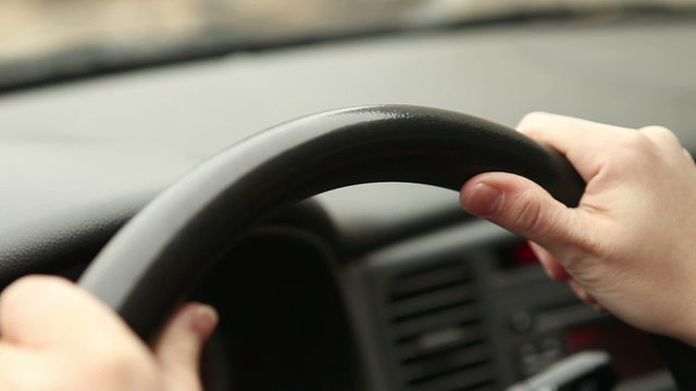 female hands on the steering wheel of the car, close-up