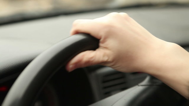 female hands on the steering wheel of the car, close-up