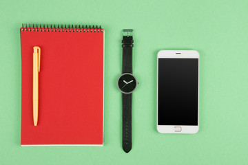 Phone, notepad, watch and pen on the color background