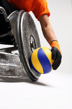 Sport na w&oacute;zku inwalidzkim.Mężczyzna na sportowym w&oacute;zku  inwalidzkim z piłką 