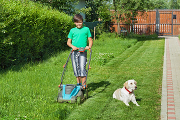 Boy cutting grass in the summer yard