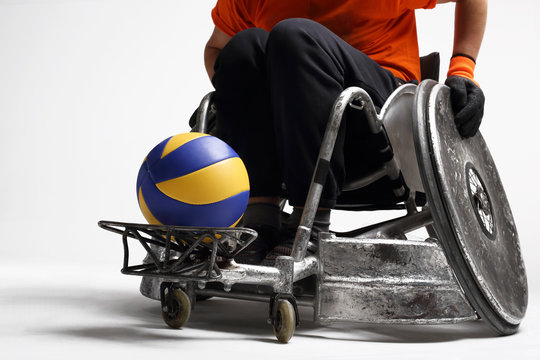 Sport os&oacute;b niepełnosprawnych.Mężczyzna na sportowym w&oacute;zku  inwalidzkim z piłką 