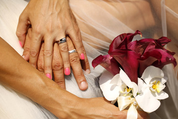 Hands of bride and groom with bouquet