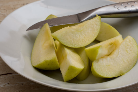 Sliced green sweet apple in the plate and knife