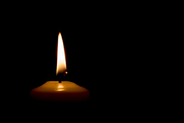 Burning candle on black background