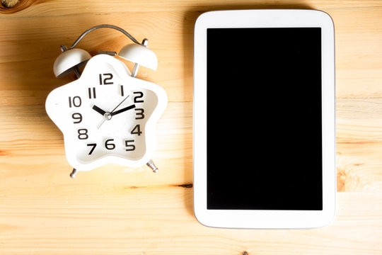 Education concept. Top view Alarm clock on wood table with Tablet PC, vintage tone