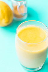 Healthy Drink Made from Turmeric Roots, Exotic Spices with Coconut Milk, Honey and Ghee on Blue Background