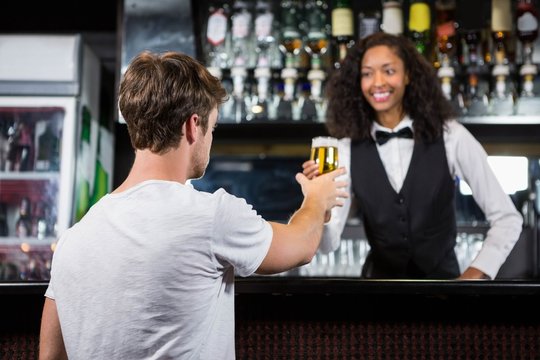 Barmaid serving beer to man