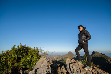 Naklejka na ściany i meble Mountain top with young southeast asian man standing