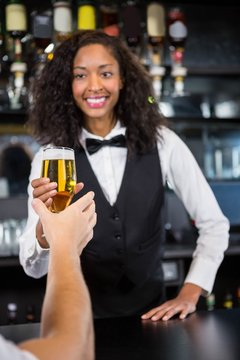 Beautiful barmaid serving beer to man